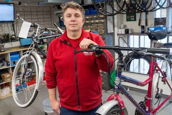 Mann ser i kamera ved siden av sykkel