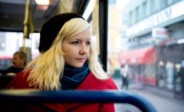 Ung kvinne sitter på trikken og ser ut av vinduet.