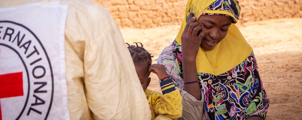 En kvinne sitter sammen sitt barn og snakker i en mobiltelefon.