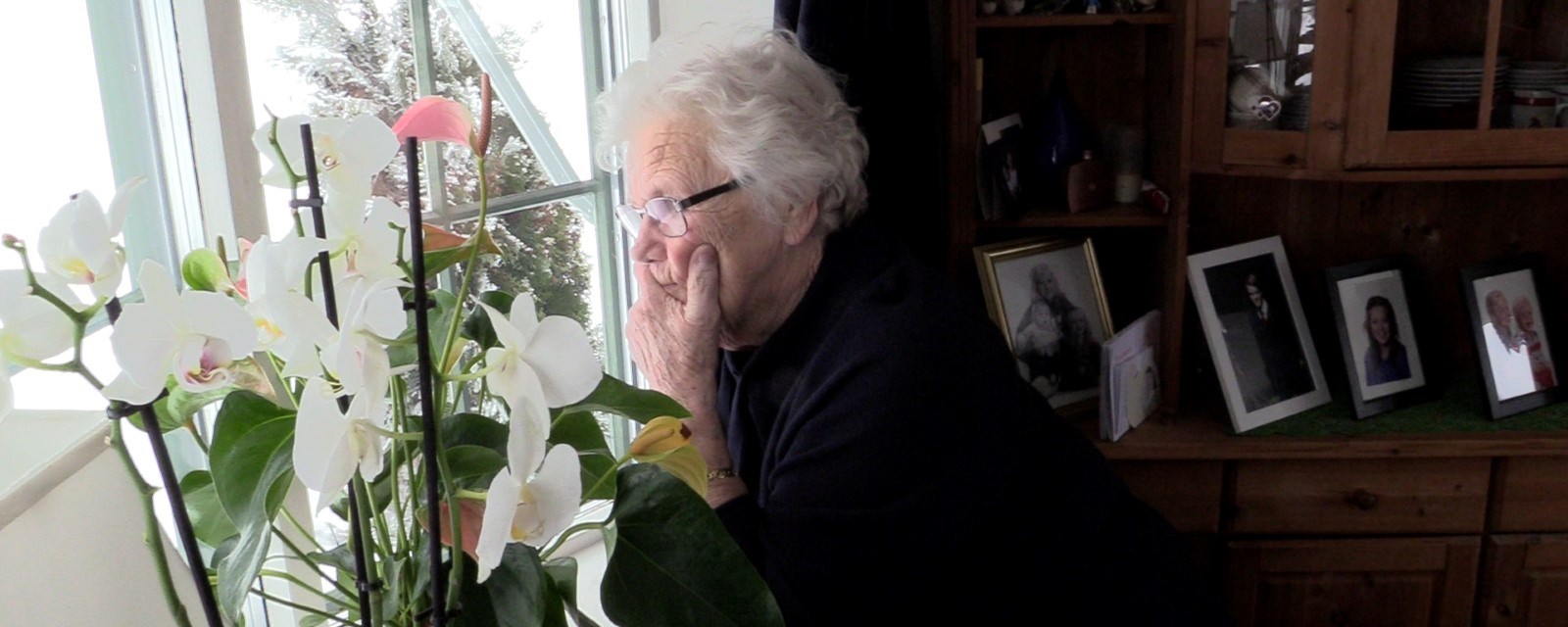 En eldre kvinne kikker ut av vinduet
