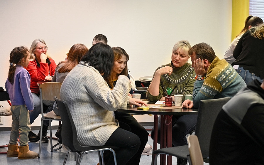 mennesker samlet rundt bord i lokaler