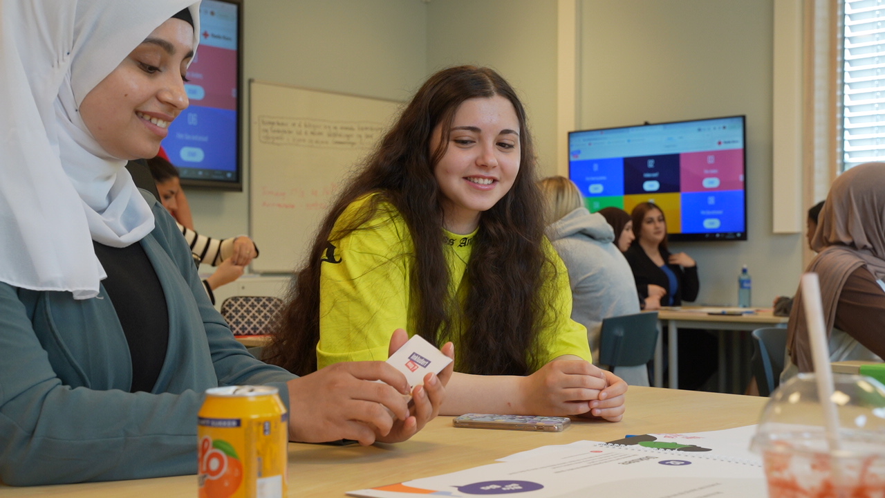 Smilende elever ved arbeidsbord