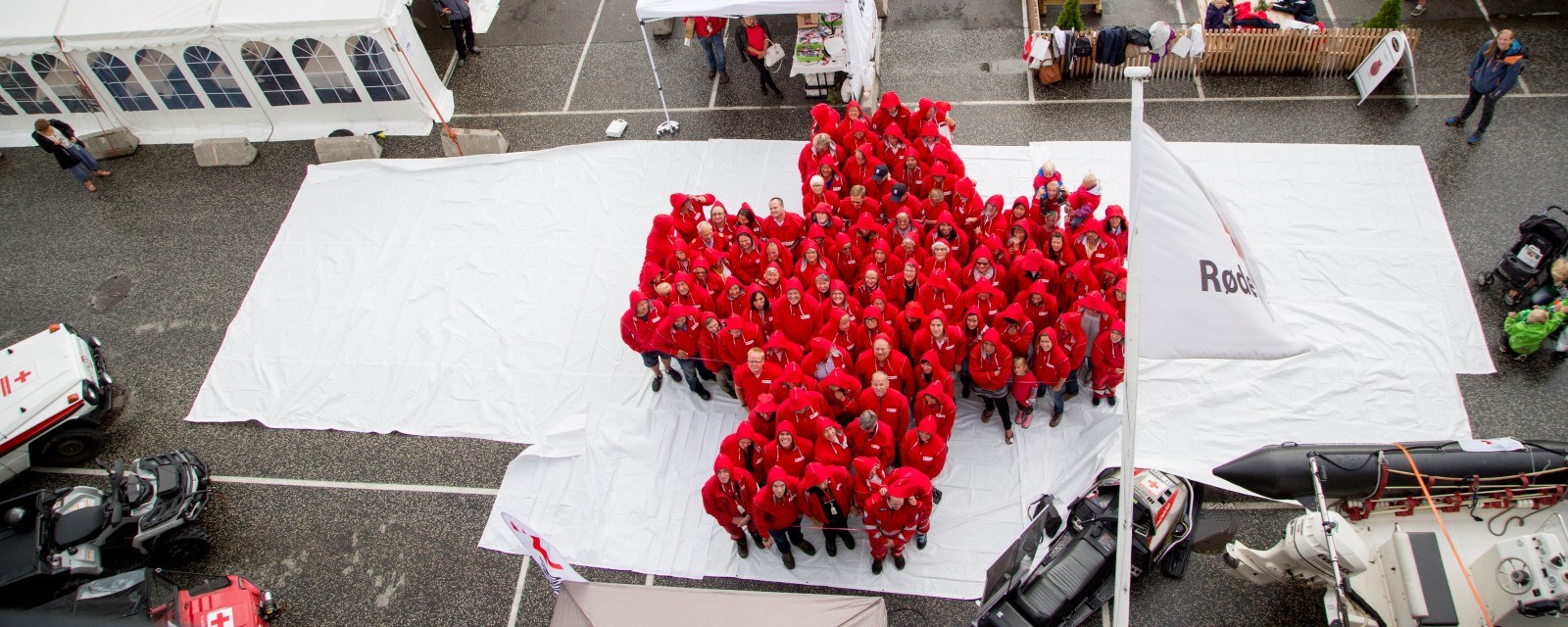 Mange mennesker kledd i rødt danner det røde korset på hvitt underlag.