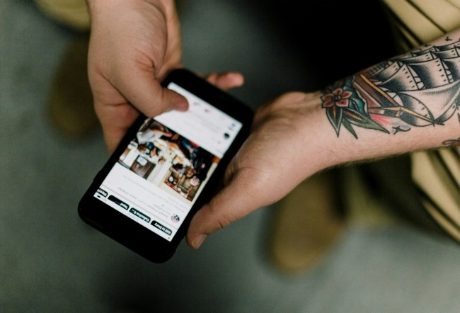 En mann sitter med en mobil i hånden og leser nyheter.