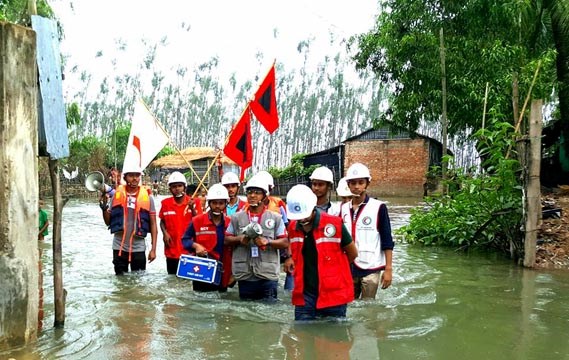En gruppe mennesker fra IFRC går i vann til midjen