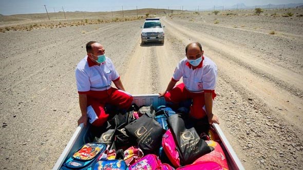 2 personer fra røde kors sitter på lasteplanet fylt av skolesekker og nødhjelp, ørken tørke