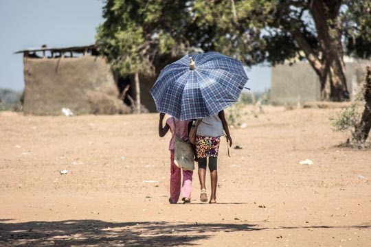 To barn går under paraply for å beskytt emot stekende sol, ørken, tørke