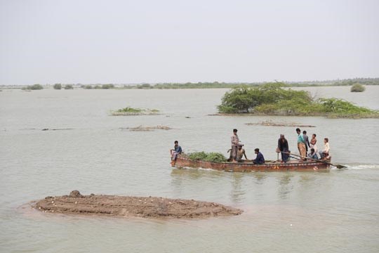 Pakistan, en båt med gress og mennesker i flomrammet område