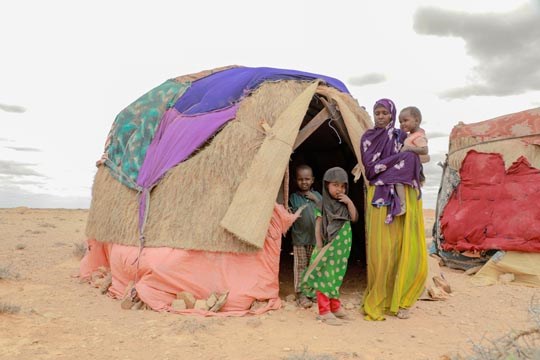 En kvinne står utenfor improvisert hjem med 3 små barn, somalia, tørke