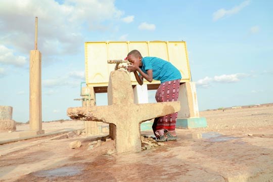 EN gutt drikker vann fra en kran, tørke, somalia