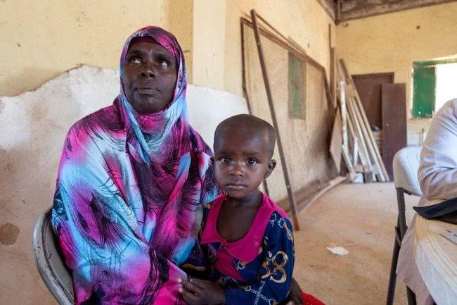 En kvinne i Somaliland sitter med et barn på fanget