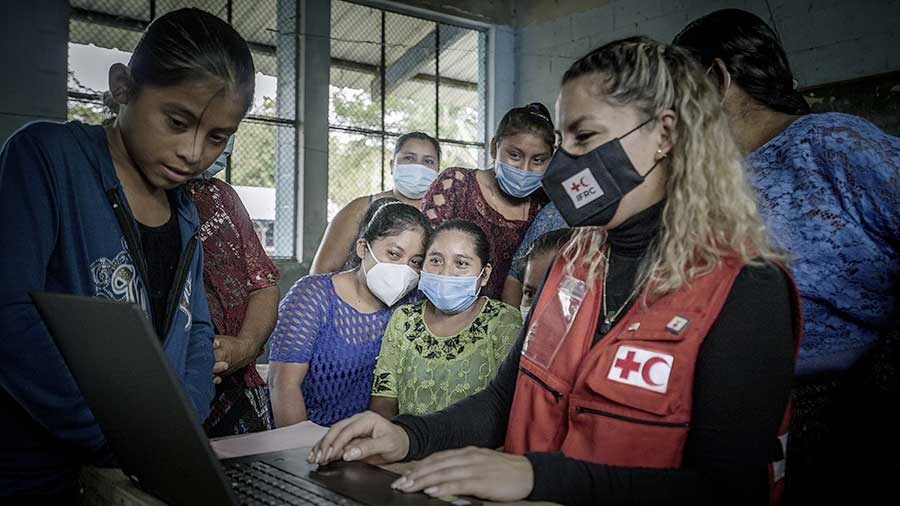 Helsepersonell fra Røde Kors  viser unge kvinner  i Guatemala om covid forebyggende arbeid