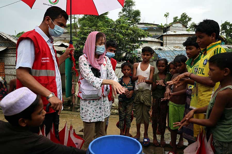 Røde Kors frivillige viser unge menn om håndvask for å begrense smitte