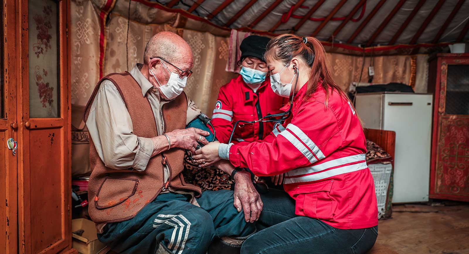 En mongolsk mann får vaksine av frivillige fra Mongolsk Røde Kors