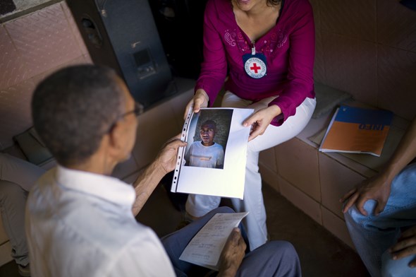 En kvinne fra Røde Kors viser frem et bilde av en person til en mann.